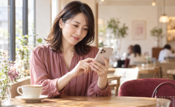 明るいカフェでスマートフォンを手にメッセージを考える女性のイメージ